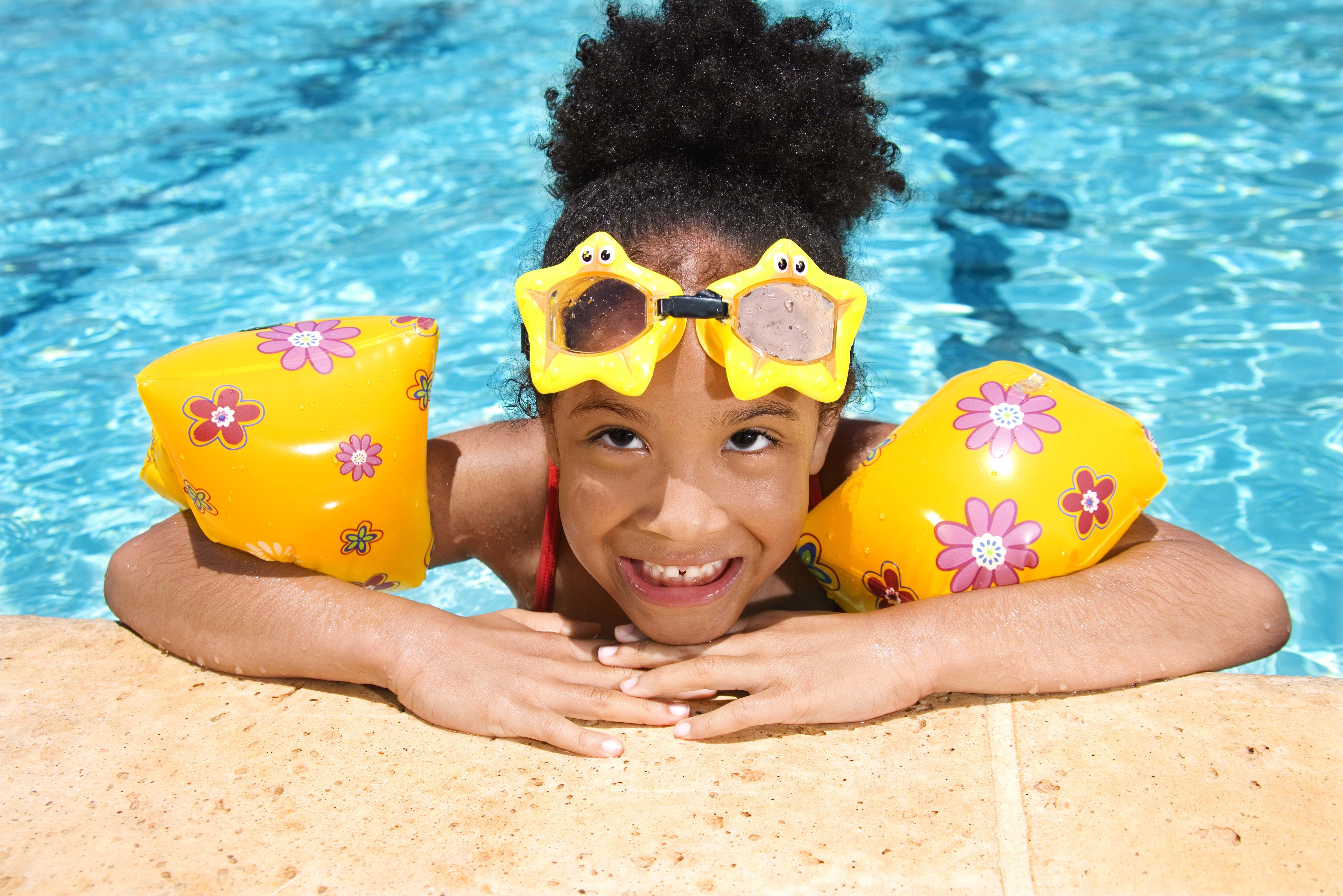 Girl with floaties and goggles in swimming pool