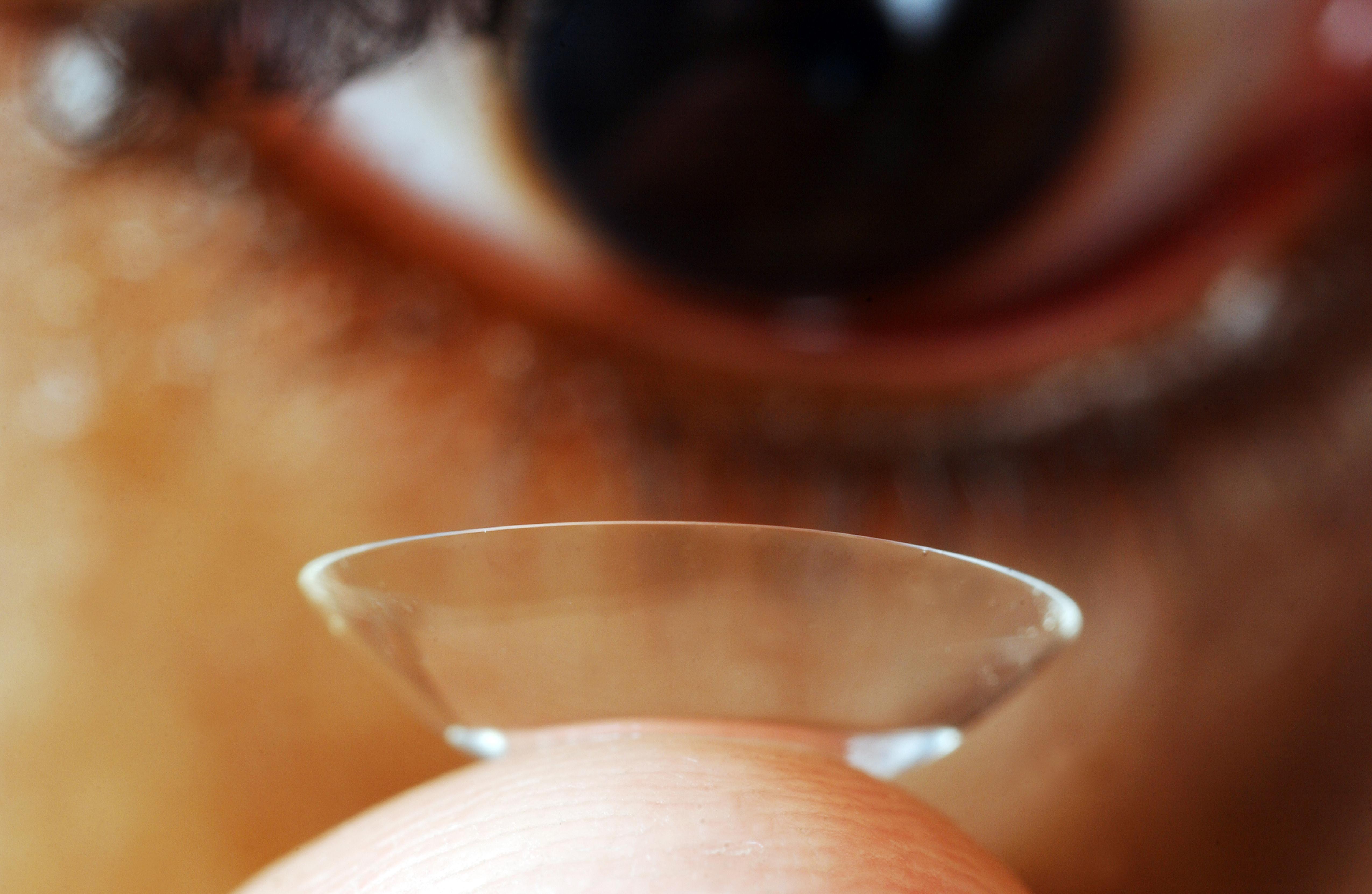 Close up of young man putting contact lens onto eye