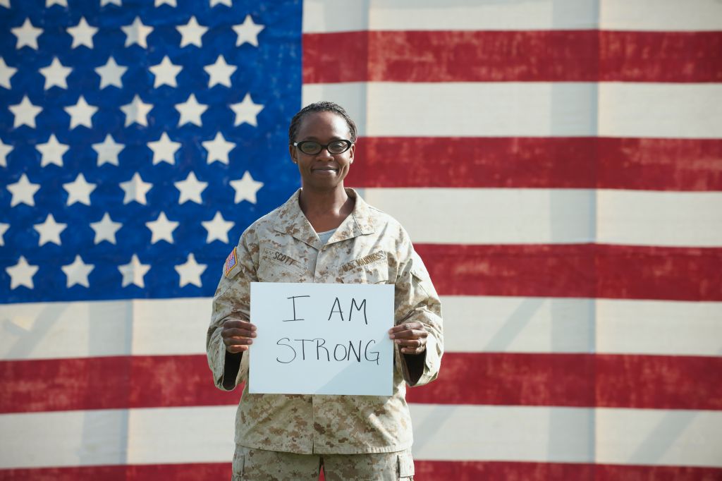 Black soldier holding I am strong sign near American flag