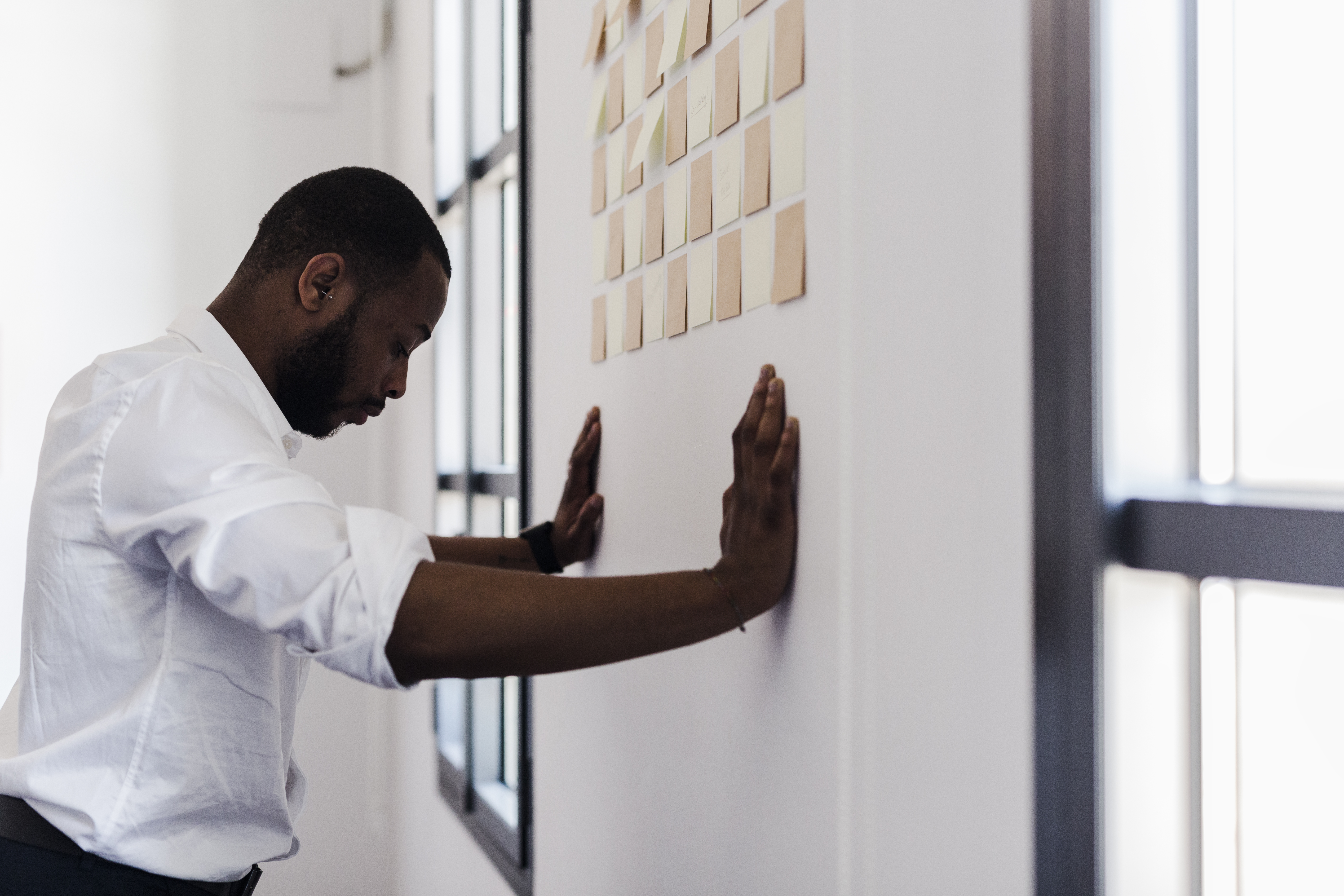 Man leaning against wall with adhesive notes in office