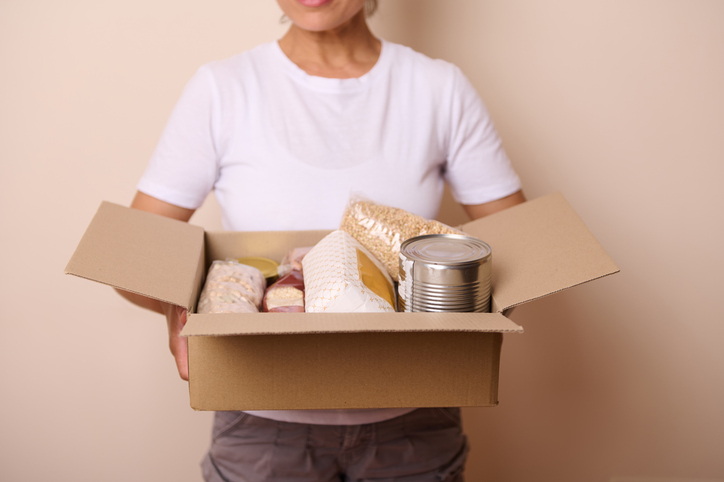 Person Holding a Box Containing Non-Perishable Food Supplies for Donation or Charity