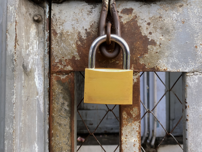Title Close-up of a Rusty Padlock and Metal Bars on a Jail Cell Door.